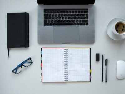 Escritorio con portátil, libreta y taza de café, plano cenital, para elegir un experto en Holded